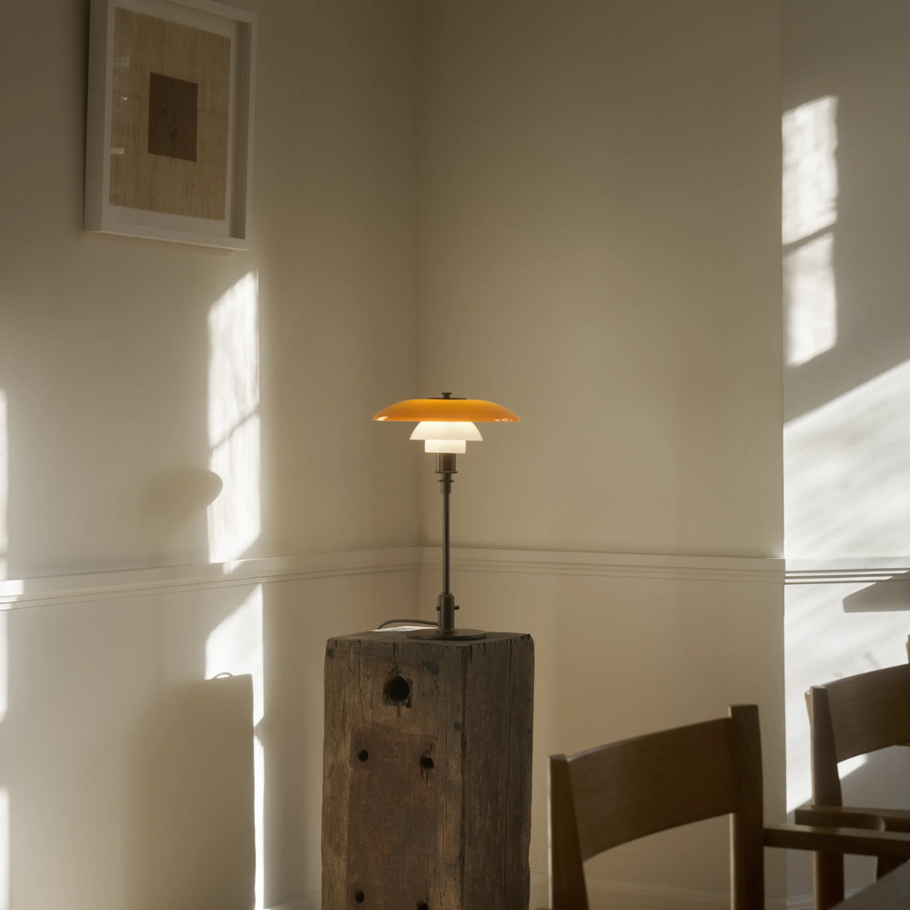The PH 3/2 Table Lamp Centenary Edition by Louis Poulsen on a side table in a dining room.