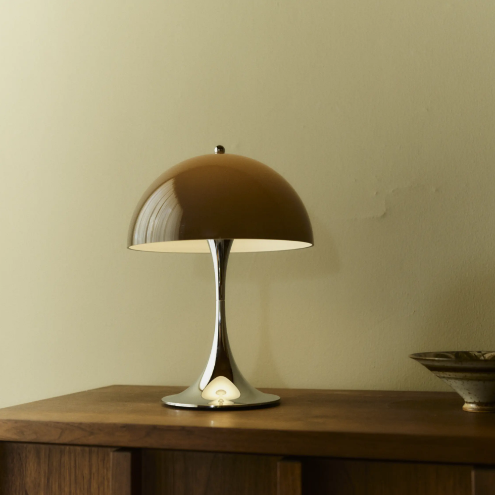 The Panthella 250 Portable Table Lamp from Louis Poulsen in Original Opal Brown on a credenza turned on.