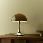 The Panthella 250 Portable Table Lamp from Louis Poulsen in Original Opal Brown on a credenza turned on.