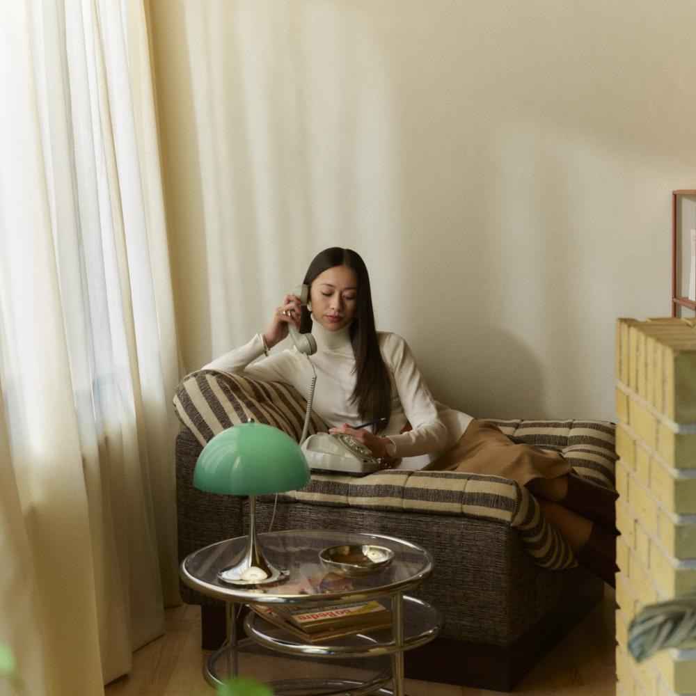 The Panthella 250 Portable Table Lamp from Louis Poulsen in Original Opal Green in a living room.
