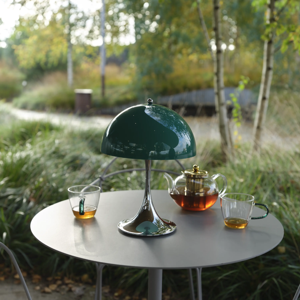 The Panthella 250 Portable Table Lamp from Louis Poulsen in Original Opal Green on an outdoor table turned off.