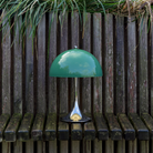 The Panthella 250 Portable Table Lamp from Louis Poulsen in Original Opal Green turned off outside.