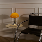 The Panthella 250 Portable Table Lamp from Louis Poulsen in Original Opal Orange on a side table.