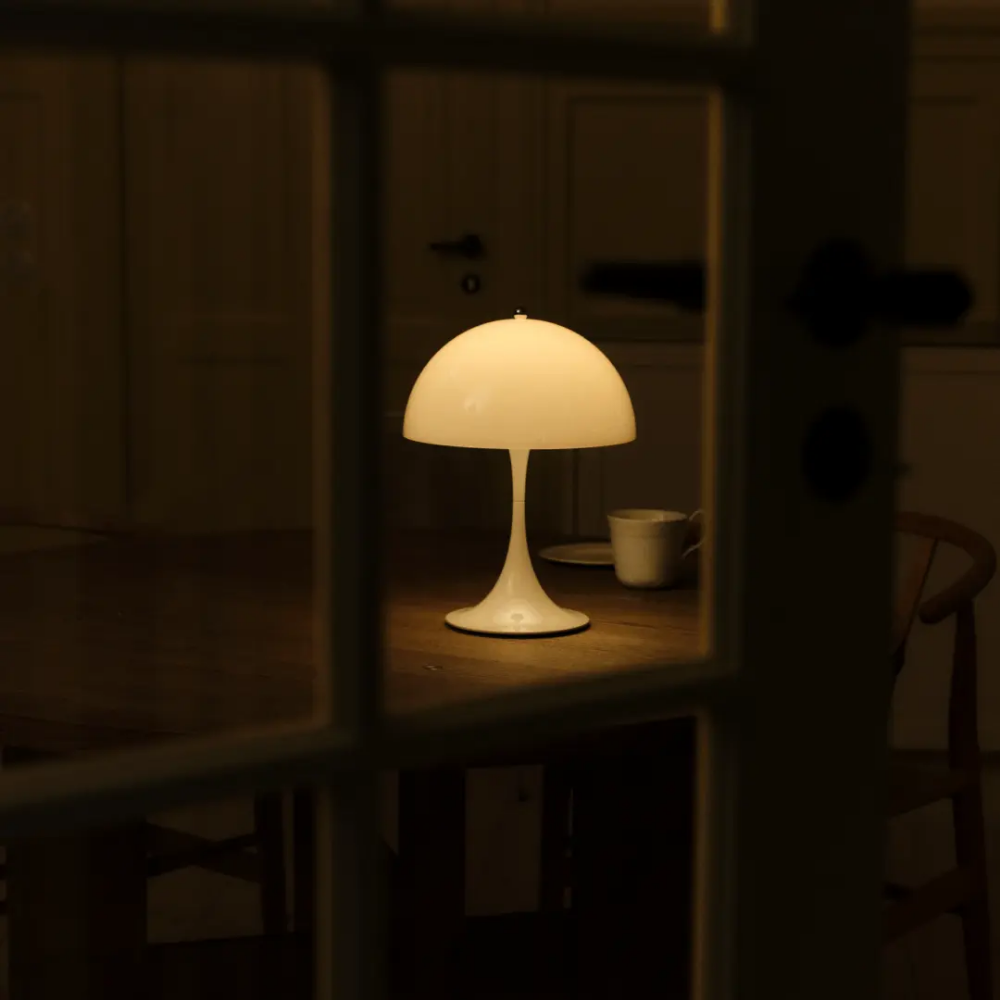The Panthella 250 Portable Table Lamp from Louis Poulsen in Opal White tin a dining room.
