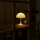 The Panthella 250 Portable Table Lamp from Louis Poulsen in Opal White tin a dining room.
