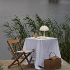 The Panthella 250 Portable Table Lamp from Louis Poulsen in Opal white on an outdoor table.