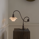 The PH 1/1 Piano Table Lamp by Louis Poulsen on a pedestal turned on.