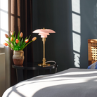 The pale rose PH 3/2 Glass Table Lamp from Louis Poulsen in a primary bedroom.