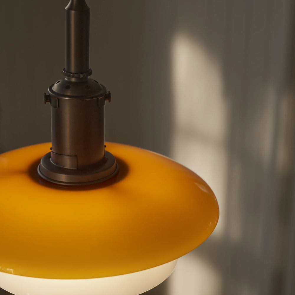 A close up of the lacquered brass suspension and amber-colored top shade of the PH 3/3 Pendant Centenary Edition by Louis Poulsen.