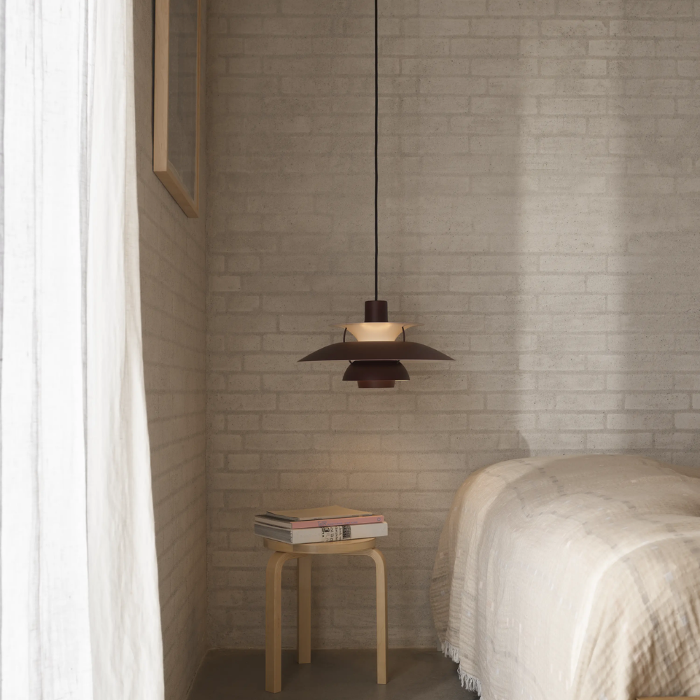 The PH 5 from Louis Poulsen in monochrome burgundy in a bedroom.