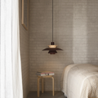 The PH 5 from Louis Poulsen in monochrome burgundy in a bedroom.