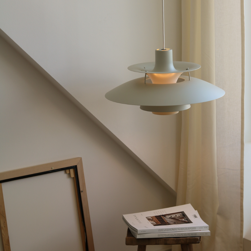 The PH 5 from Louis Poulsen in monochrome pale pewter in a living room over a side table.
