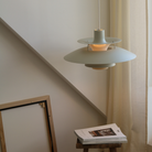 The PH 5 from Louis Poulsen in monochrome pale pewter in a living room over a side table.