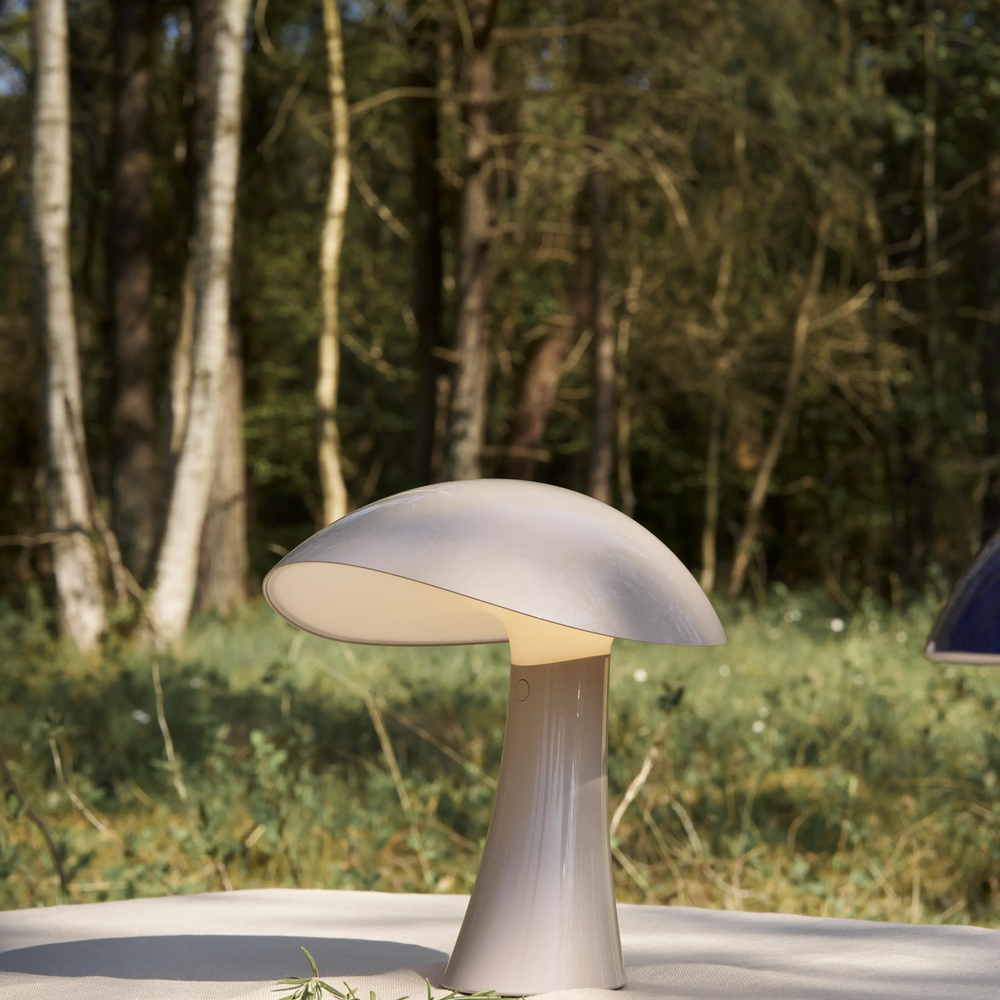 Rumee 220 Portable Lamp in Earth Grey on an outdoor table.