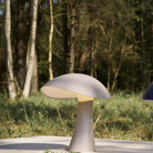 Rumee 220 Portable Lamp in Earth Grey on an outdoor table.