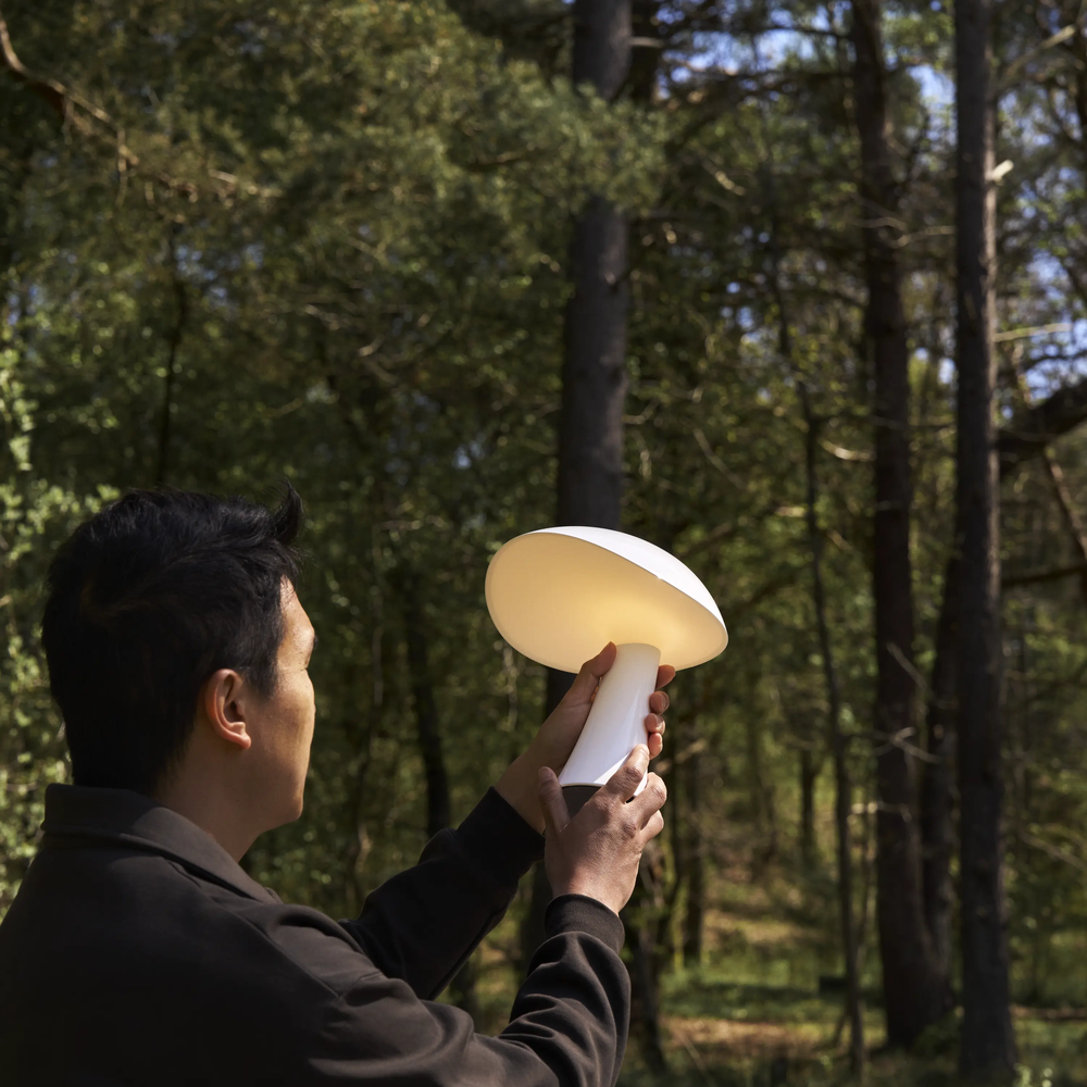 Rumee 220 Portable Lamp in Cloud White being held by designer, Gabriel Tan.