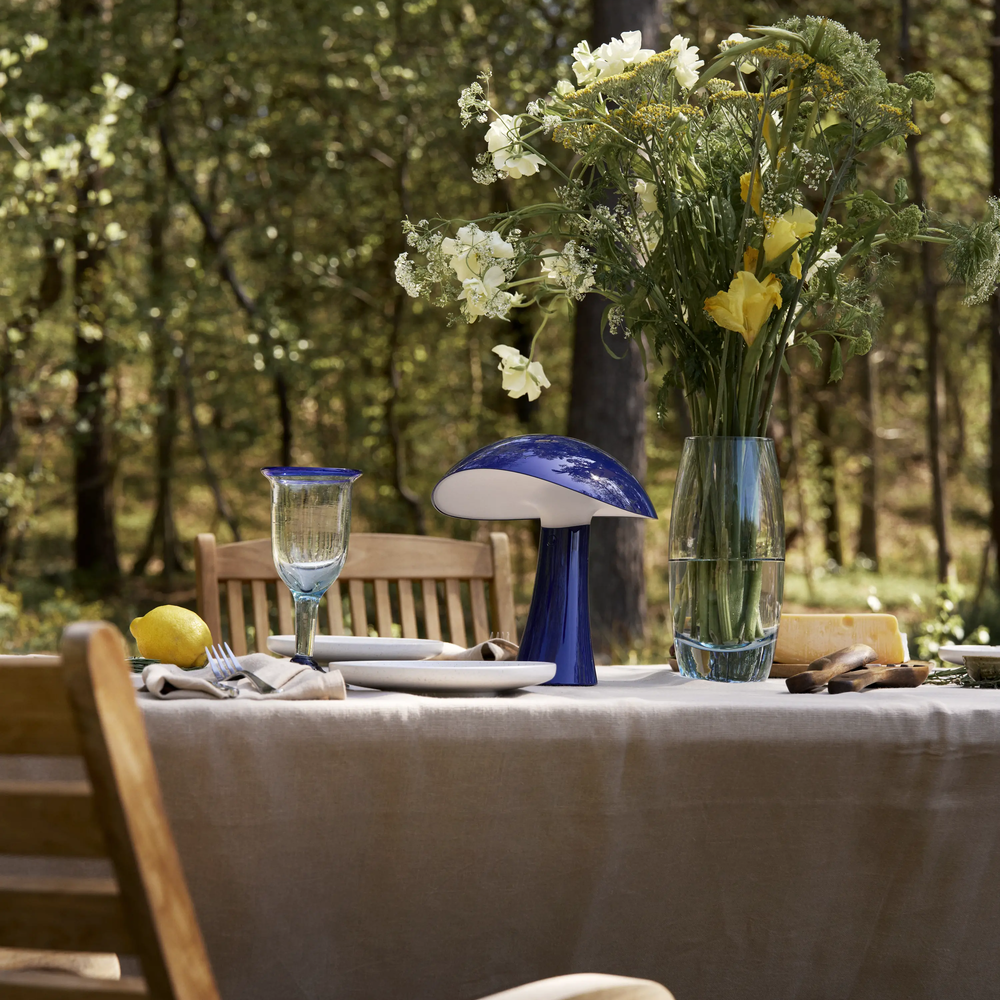 Rumee 220 Portable Lamp in Night Blue on an outdoor dining table.