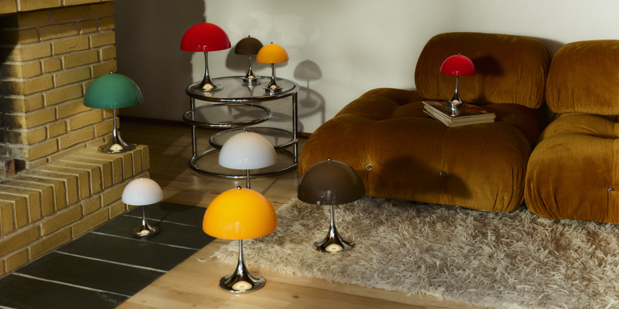 A collection of Panthella Portable Lamps from Louis Poulsen in multiple colors beside a sofa.