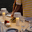 The Bicoca Portable Table Lamp from Marset in off-white in an outdoor dining room.