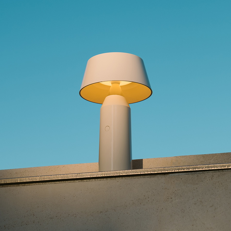 The Bicoca Portable Table Lamp from Marset in off-white outdoors.