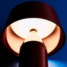 The Bicoca Portable Table Lamp from Marset in red wine in a bedroom.