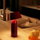 The Bicoca Portable Table Lamp from Marset in red wine in a living space.