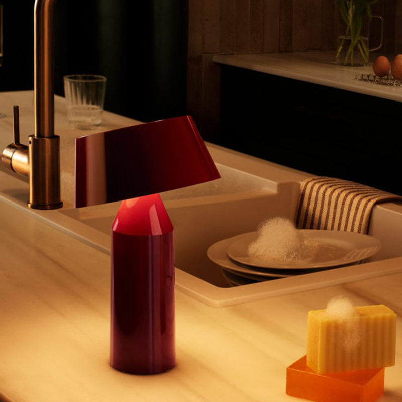 The Bicoca Portable Table Lamp from Marset in red wine in a living space.