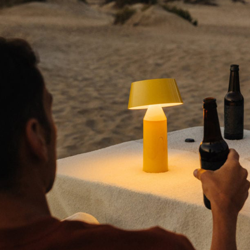 The Bicoca Portable Table Lamp from Marset in yellow in an outdoor lounge.