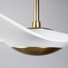 The satin brass and matte white IC/Brisa DC - 56″ from Modern Fan Co. in a view from the side within a living space.