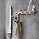 The Avail Coat Rack Oak/Copper Brown from Muuto in a bathroom. all-groups