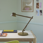 The brown green Dedicate Table Lamp from Muuto used as a desk light.