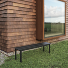 The black Linear Steel Bench from Muuto used as a garden bench.