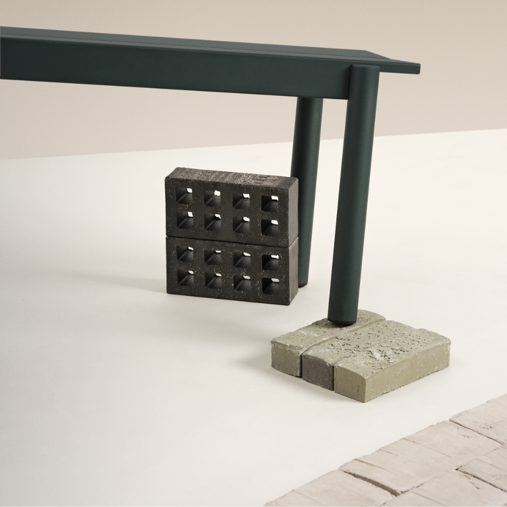 The dark green Linear Steel Bench from Muuto in a studio living space.