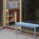 The pale blue Linear Steel Bench from Muuto outdoors beside an entryway.
