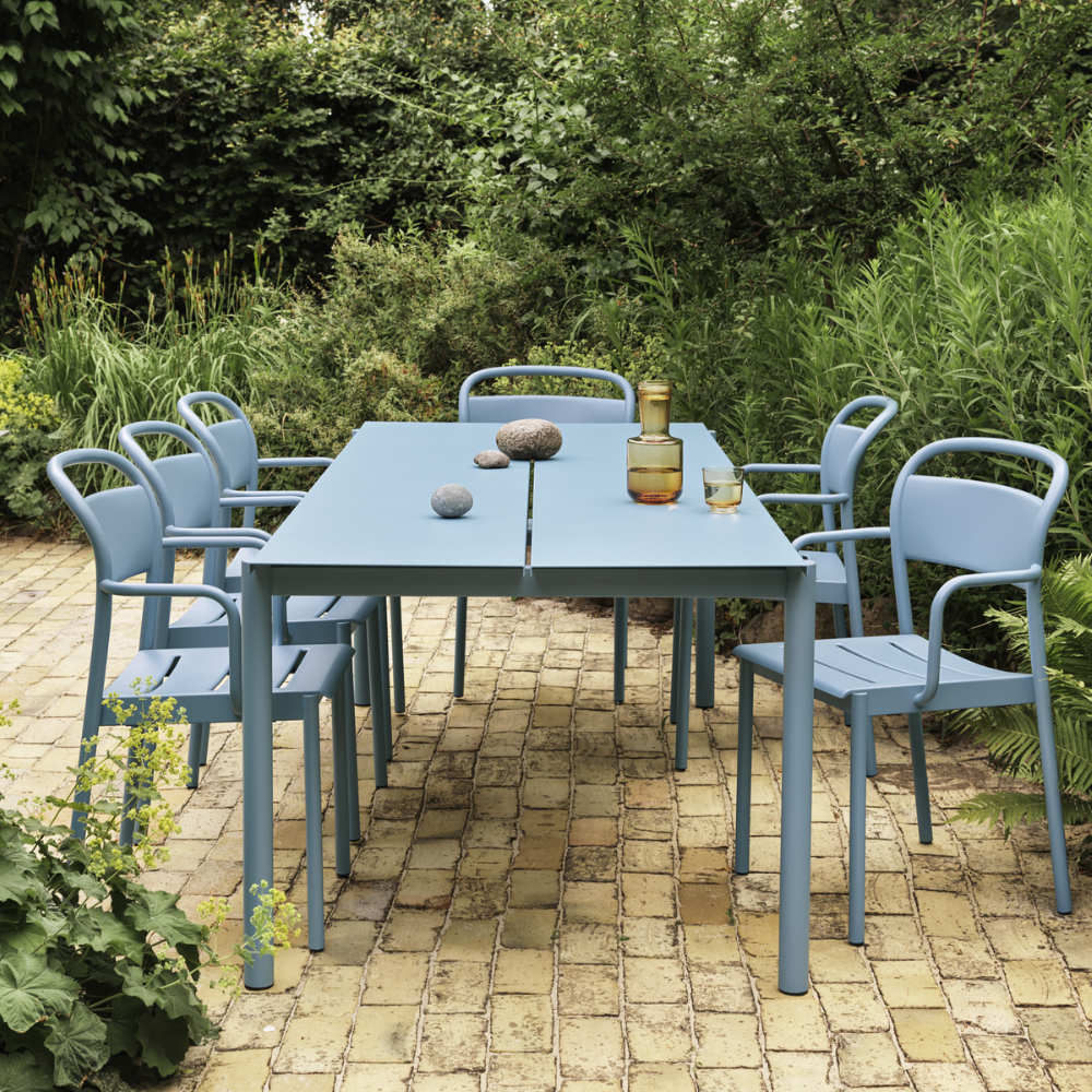 The pale blue Linear Steel Table from Muuto in a garden courtyard.