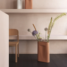 The Ridge Vase from Muuto in terracotta in a primary bedroom.