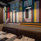 The Lampe de Marseille Mini Wall Sconce from Nemo in gray in a restaurant.