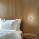 The Totem Puck Ceiling or Wall Light from Pablo Designs used as a bedside light, beside a bed. all-groups