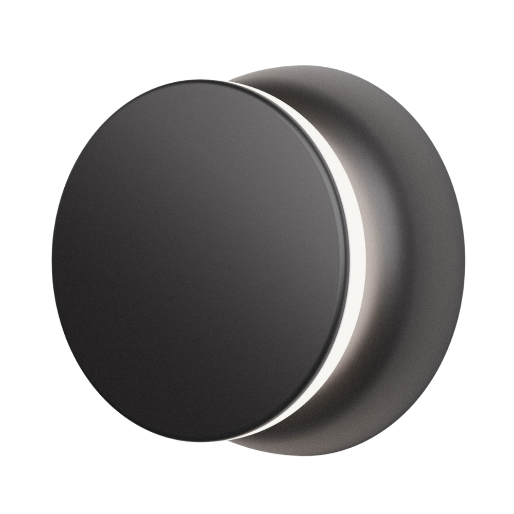 The black and black Totem Puck Ceiling or Wall Light from Pablo Designs turned on, close up.