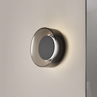 The Totem Sconce by Pablo Designs in Black / Black / Smoke turned on in a living room. all-groups