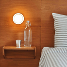 The Dimple Sconce by RBW with White Interior and Natural Anodized installed on a headboard. all-groups