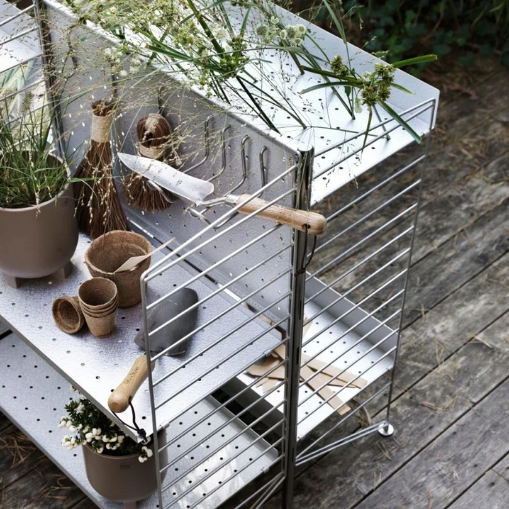 The String Outdoor Bundle from String Furniture being used as garden tool storage.