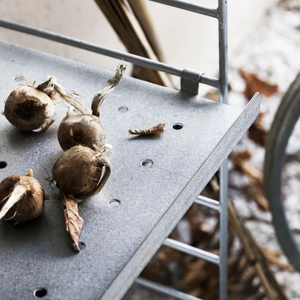 The String Outdoor galvanized metal shelf from String Furniture on a patio.