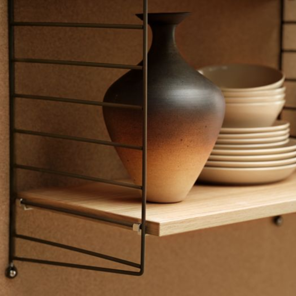 The String System by String Furniture dark brown panels with oak shelves with plates on it.