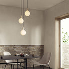 The Triple Pendant in Brass + Sphere IV, three-light fixture by Tala US over a dining table.