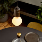The Sphere II E26 Dim-to-Warm LED Bulb by Tala Lighting with graphite pendant fitting over dining table.