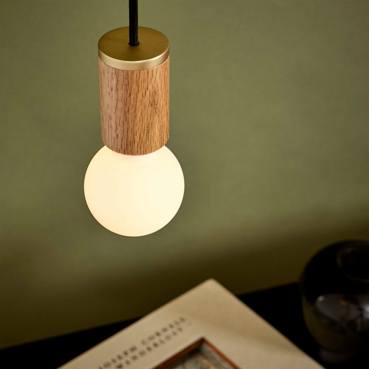 The Sphere II E26 Dim-to-Warm LED Bulb by Tala Lighting with oak pendant fitting.