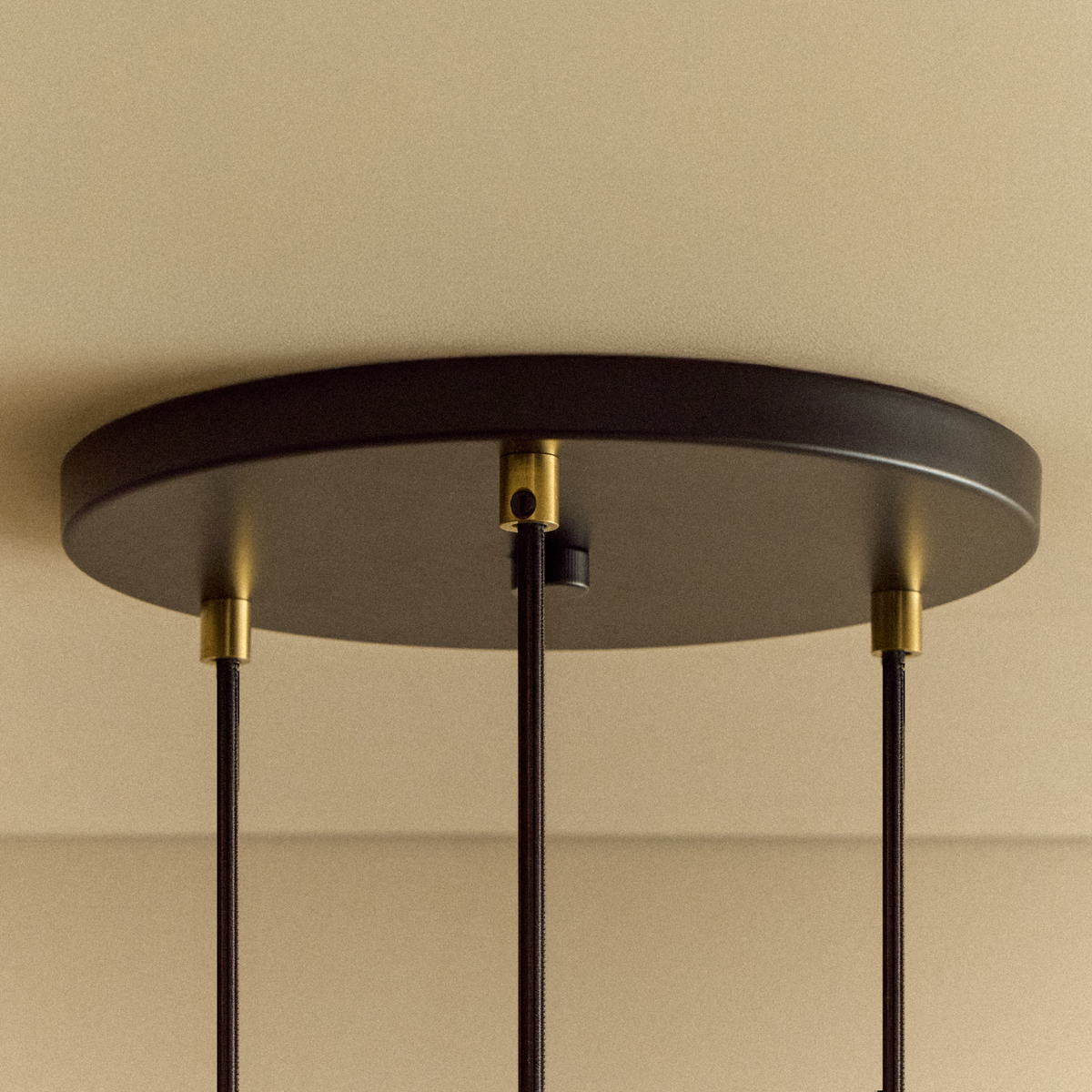 The black canopy of the Triple Pendant in Brass + Sphere IV by Tala US.