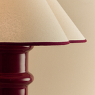 Close-up of Heath lamp with a beige shade and red base.