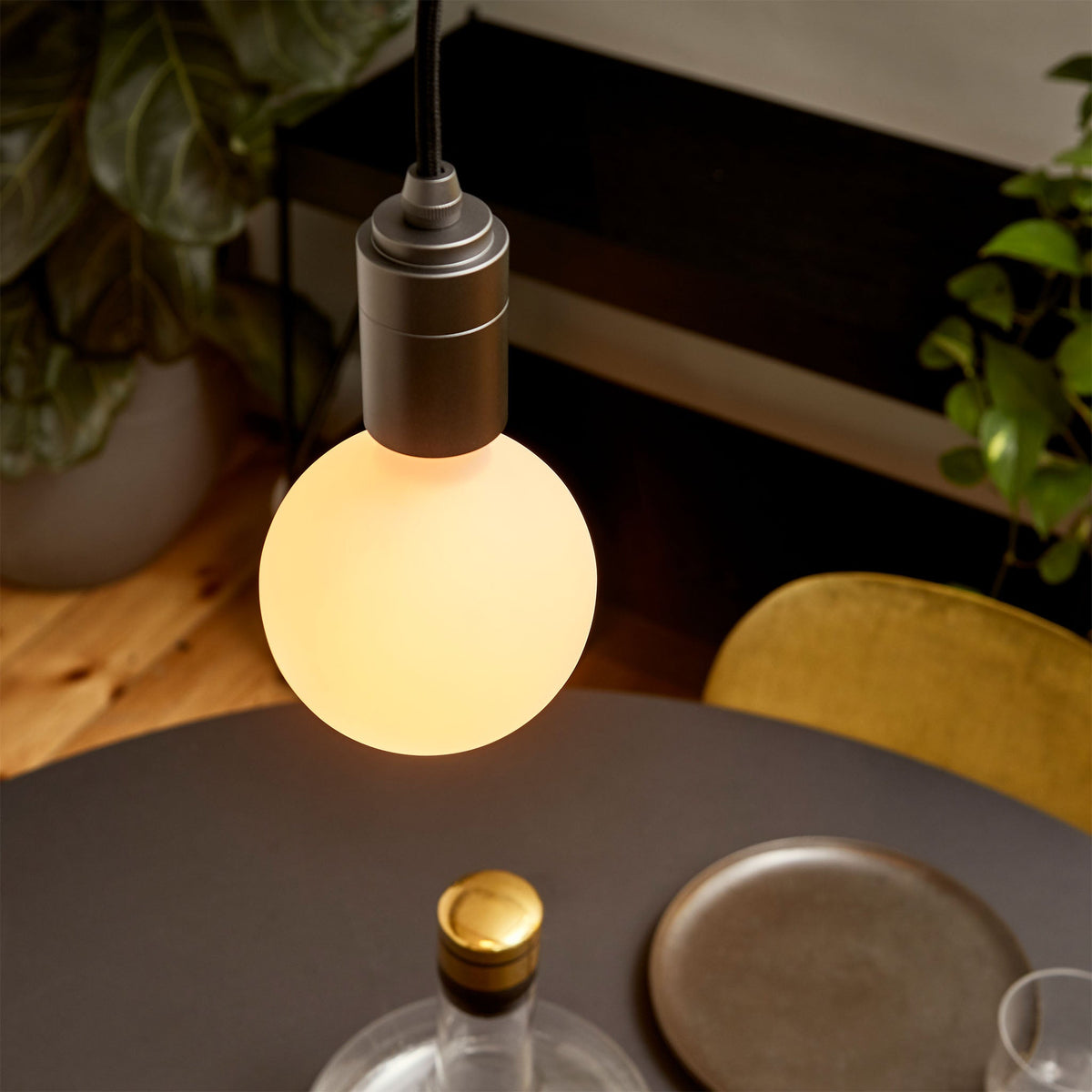 The Sphere III E26 Dim-to-Warm LED Bulb by Tala Lighting over a dining room table.